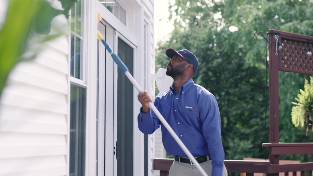 American Pest technician dewebbing the exterior of a home