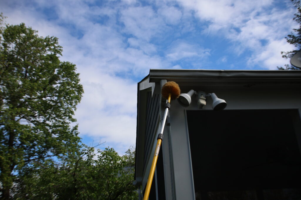 American Pest technician dewebbing eaves