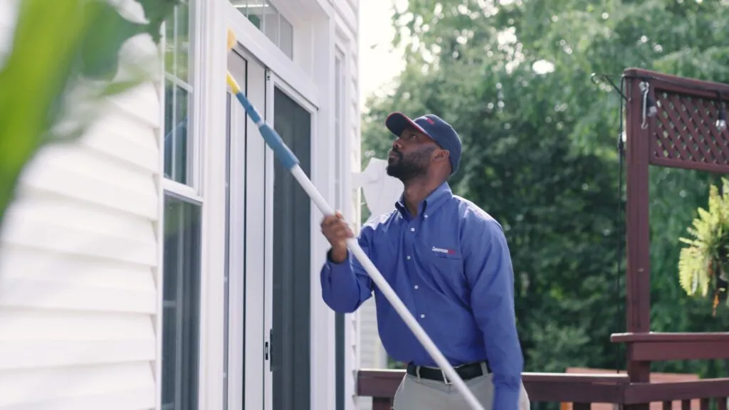 American Pest technician dewebbing the exterior of a home